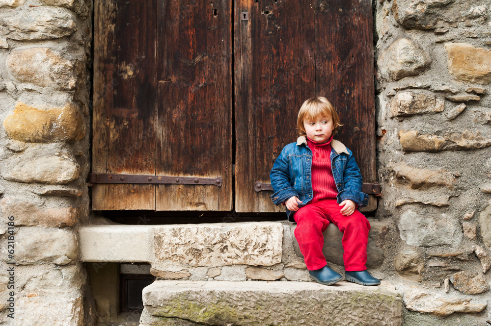 Adorable toddler boy sitting on steps outdoors