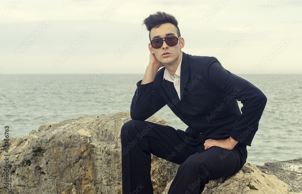 Young businessman wearing sunglasses relax on a beach