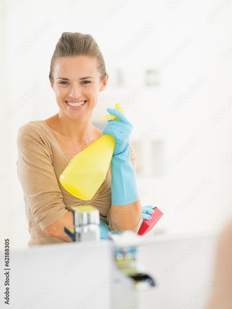 Portrait of smiling young housewife in gloves with spray bottle Portrait of smiling young housewife in gloves with spray bottle