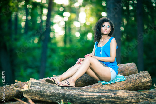 Beautiful Young Woman sitting on log posing