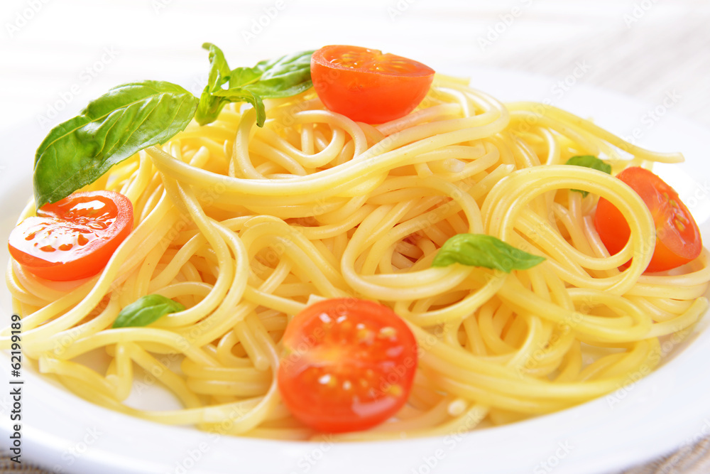 Delicious spaghetti with tomatoes on plate on table close-up Delicious spaghetti with tomatoes on plate on table close-up