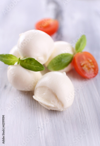 Tasty mozzarella cheese with basil and tomatoes, on wooden