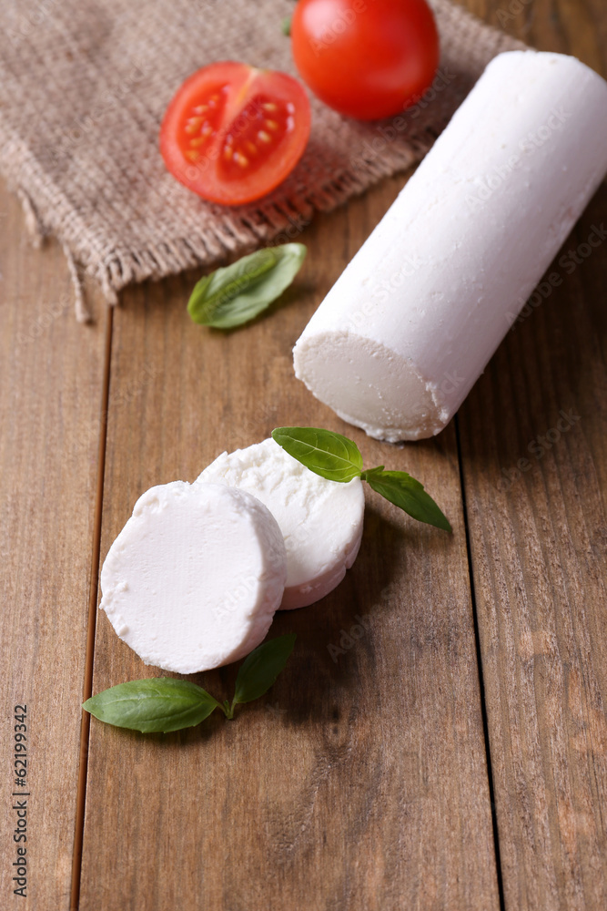Tasty bushe cheese with basil and tomato, on wooden table Tasty bushe cheese with basil and tomato, on wooden table