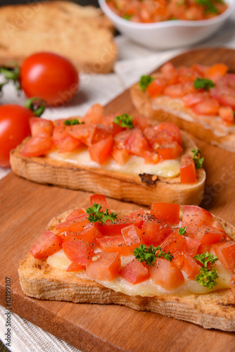 Delicious bruschetta with tomatoes on cutting board close-up