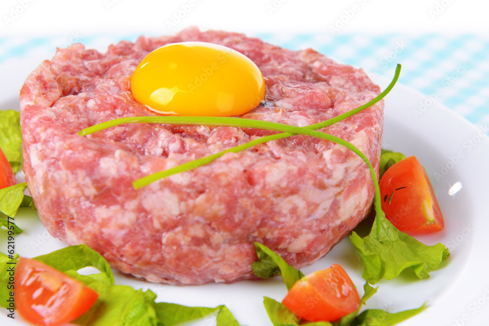Delicious steak tartare with yolk on plate on table close-up Delicious steak tartare with yolk on plate on table close-up