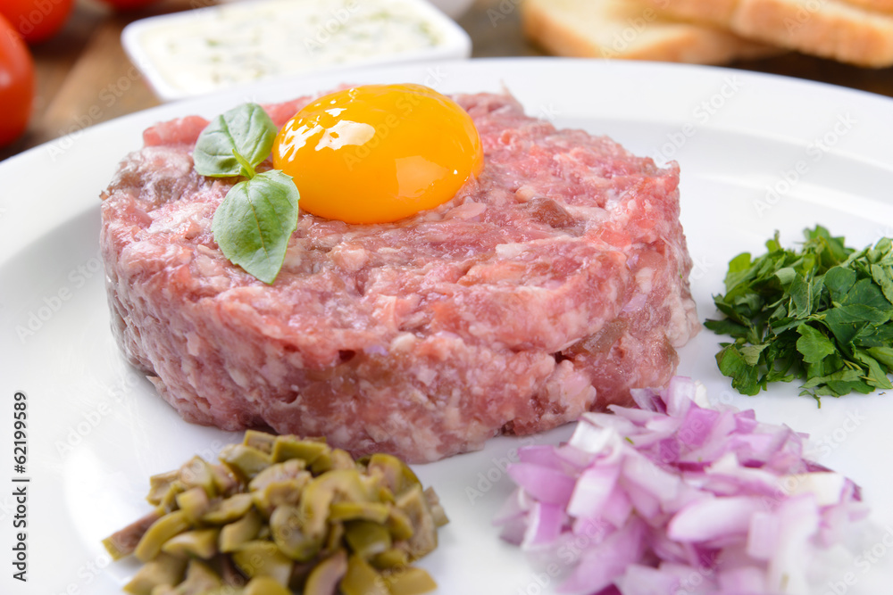Delicious steak tartare with yolk on plate on table close-up Delicious steak tartare with yolk on plate on table close-up