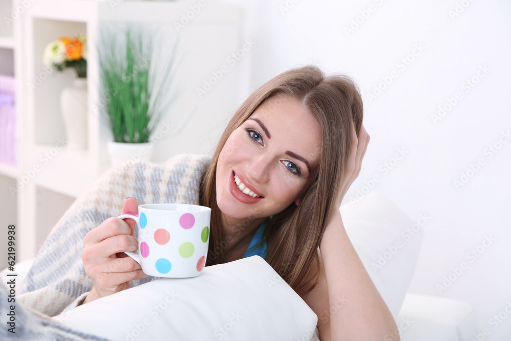 Young woman resting with cup of hot drink on sofa at home Young woman resting with cup of hot drink on sofa at home