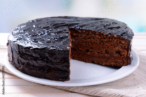 Delicious chocolate cake on plate on table on light background photo