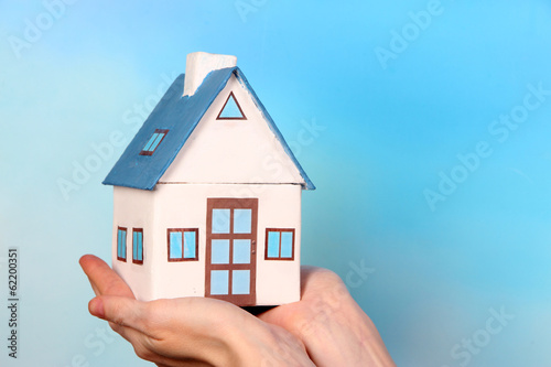 Little paper house in hand close-up, on light background