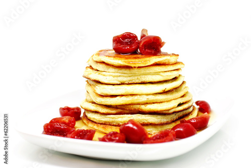 Delicious pancakes with maple syrup and sweet cherries