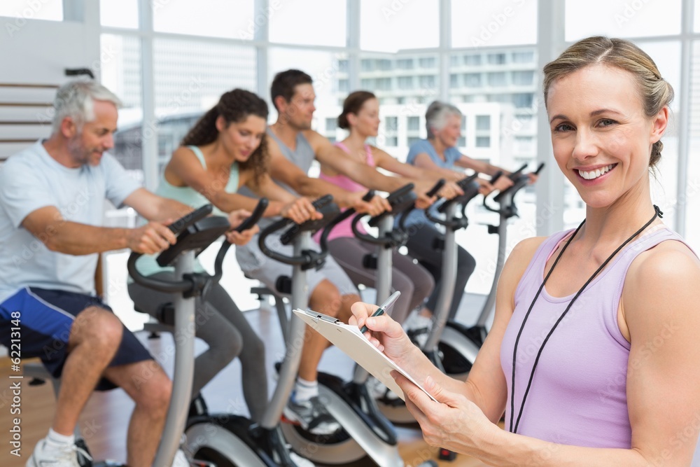 Trainer with people working out at spinning class Trainer with people working out at spinning class