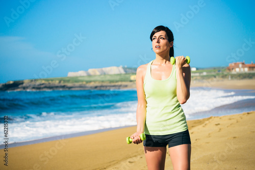 Fitness woman working out with dumbbells outdoor