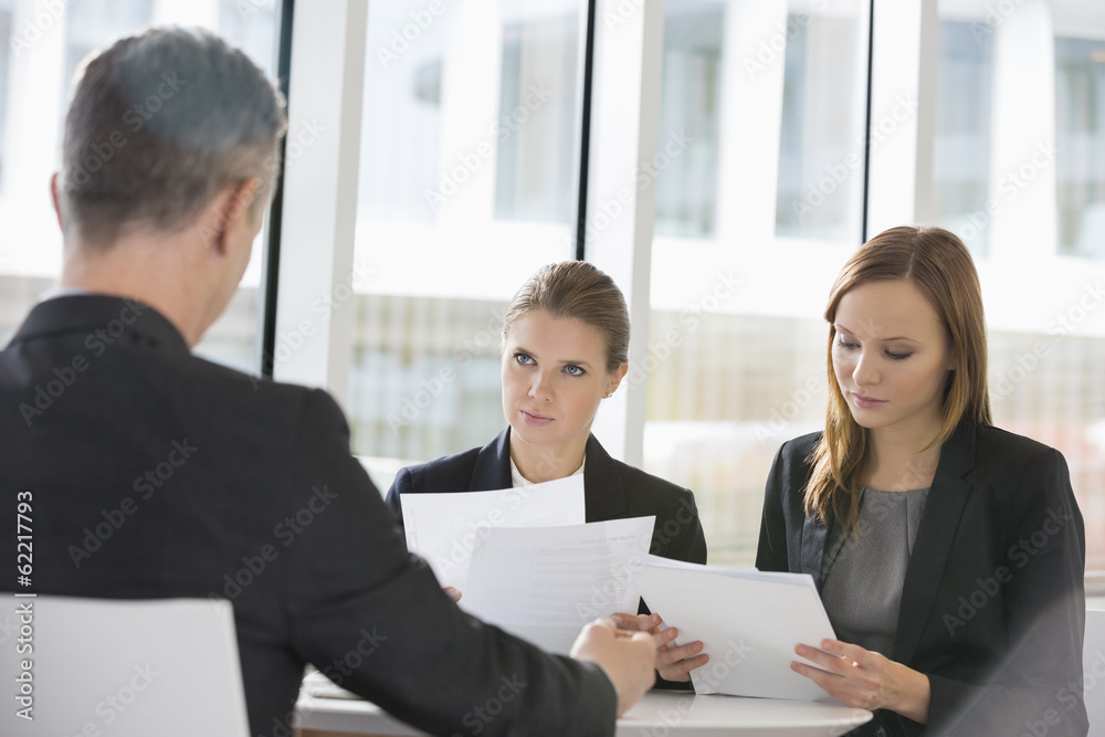 Business people discussing paperwork in office cafeteria Business people discussing paperwork in office cafeteria