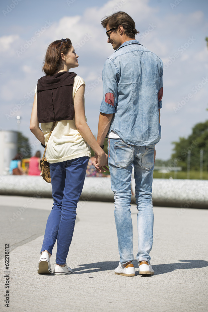 Young couple looking at each other while holding hands on street Young couple looking at each other while holding hands on street