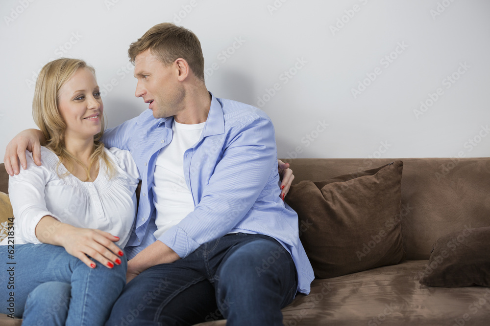 Loving mid adult couple sitting on sofa at home Loving mid adult couple sitting on sofa at home