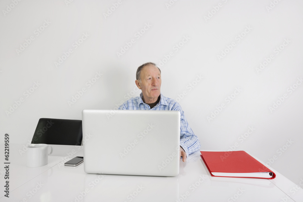 Thoughtful senior businessman using laptop at office desk Thoughtful senior businessman using laptop at office desk