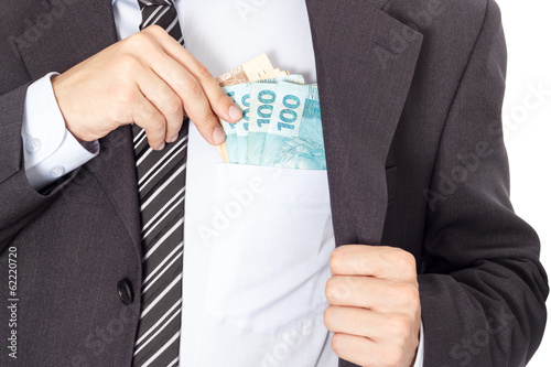 A businessman in a suit putting money in his pocket