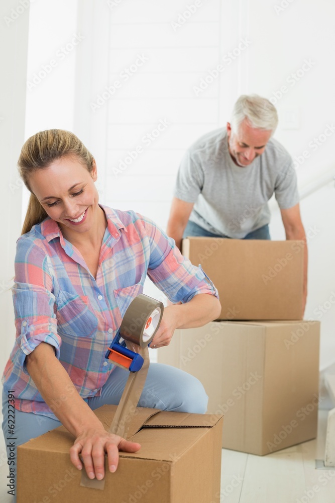 Happy couple sealing cardboard moving boxes Happy couple sealing cardboard moving boxes
