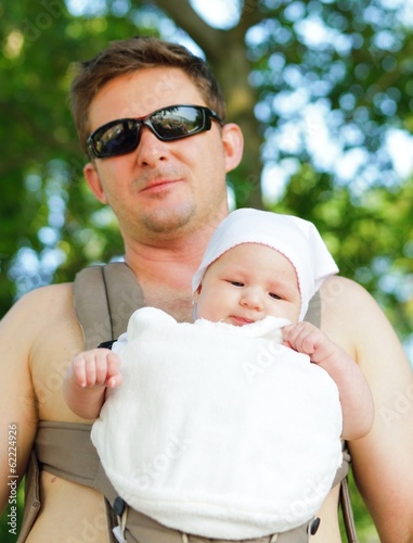 Happy father carries his baby in the carrier.