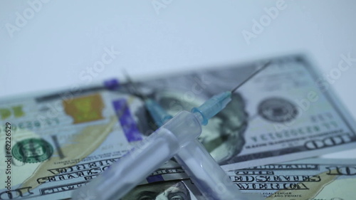 Medical syringes and money in rotation on  white background
