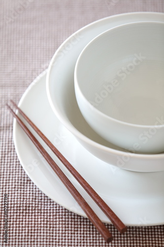 Empty white plate and bowl with chopsticks