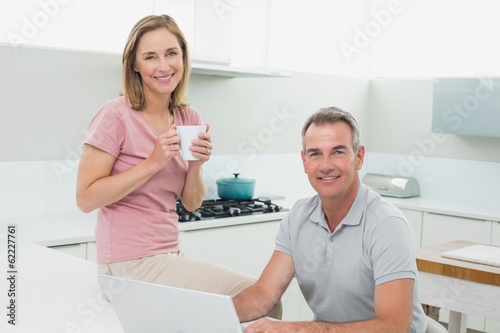 Portrait of a happy couple using laptop in kitchen