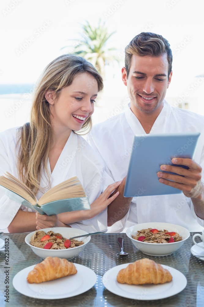 Couple with book and digital tablet on breakfast table