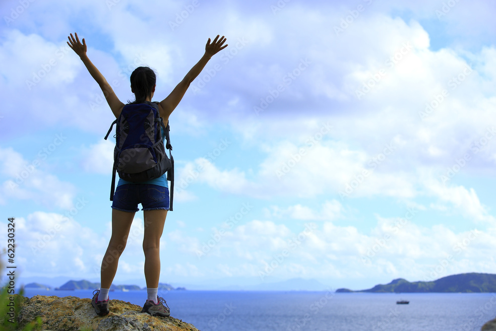 cheeering woman hiker on seaside mountain peak cheeering woman hiker on seaside mountain peak