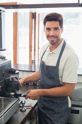 Smiling barista preparing espresso at coffee shop