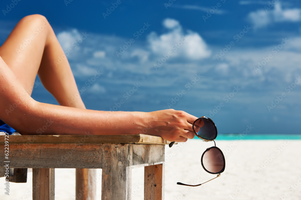 Woman at beach holding sunglasses