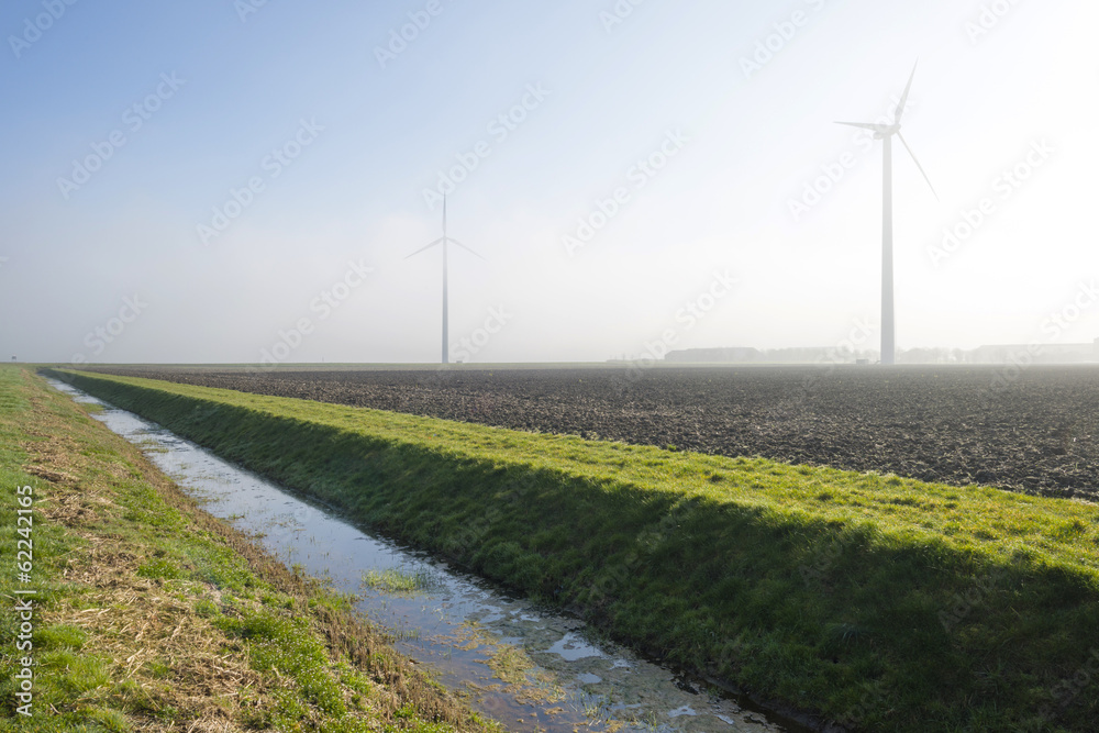 Wind turbines in a hazy field in sunlight