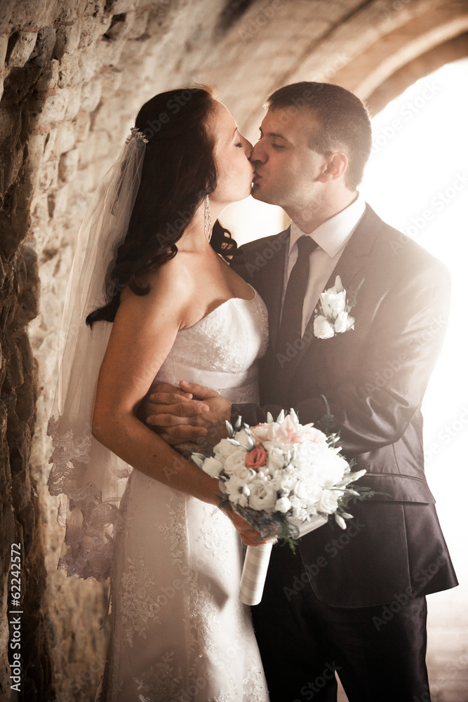 bride and groom kissing in ancient tunnel made of bricks bride and groom kissing in ancient tunnel made of bricks