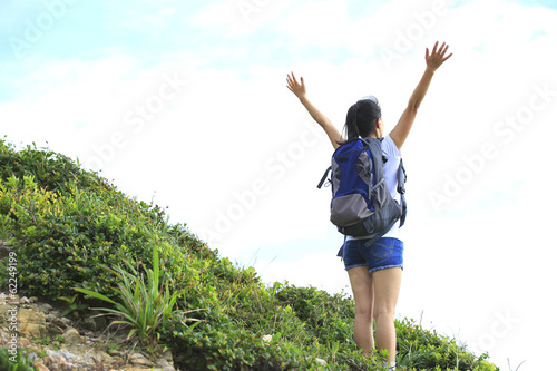 cheeering woman hiker  on seaside mountain peak