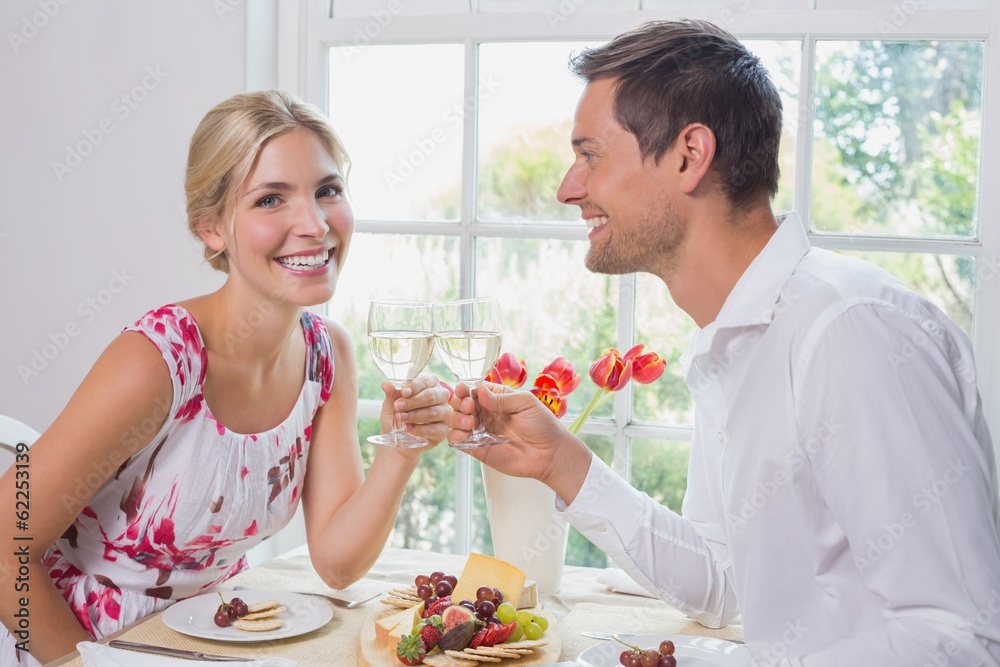 Happy young couple toasting wine glasses over food Happy young couple toasting wine glasses over food