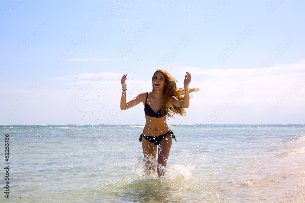 Naklejka premium Beautiful young woman running by tropical sea