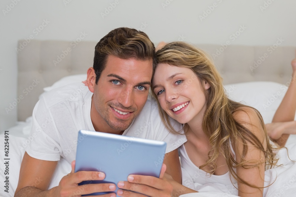 Smiling couple using digital tablet in bed Smiling couple using digital tablet in bed