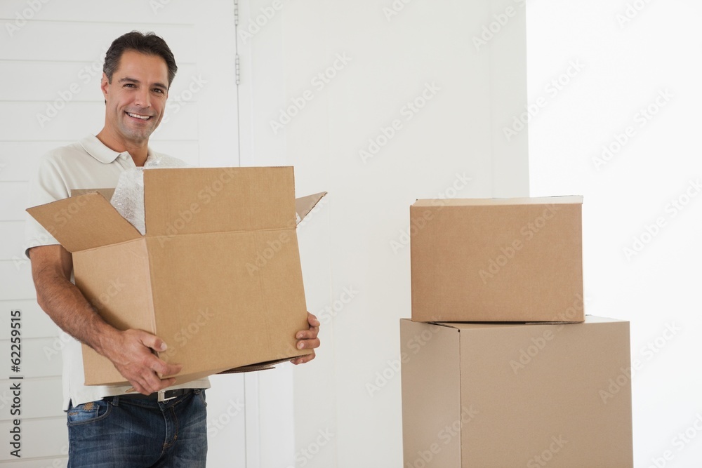 Smiling man carrying boxes in new house Smiling man carrying boxes in new house