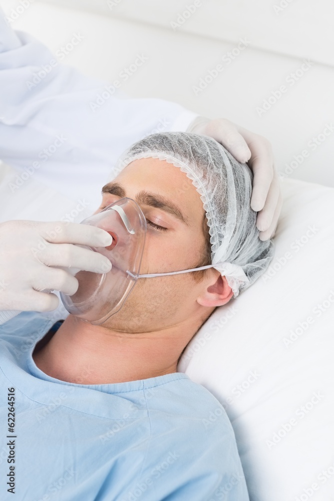 Doctor adjusting oxygen mask on male patient Doctor adjusting oxygen mask on male patient