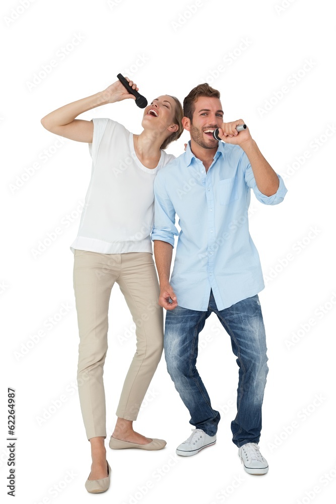 Cheerful couple singing into microphones Cheerful couple singing into microphones