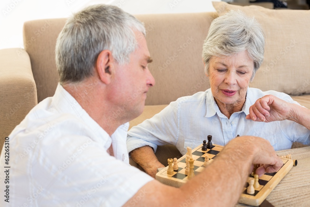 Senior couple sitting on floor playing chess Senior couple sitting on floor playing chess