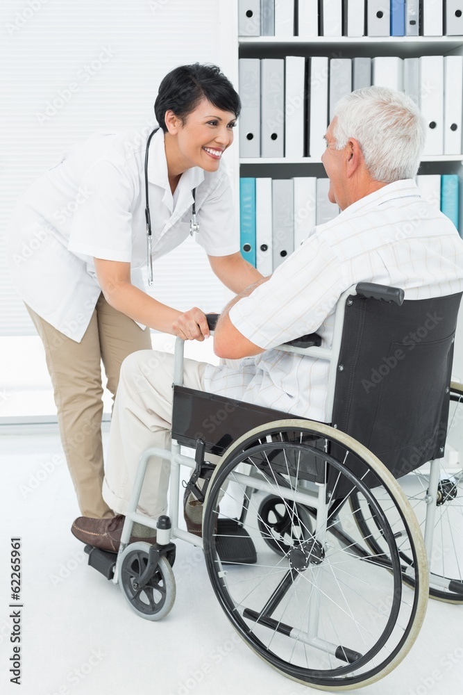 Female doctor talking to senior patient in wheelchair Female doctor talking to senior patient in wheelchair