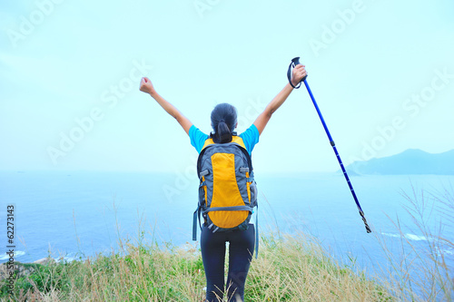 cheeering woman hiker open arms seaside mountain peak