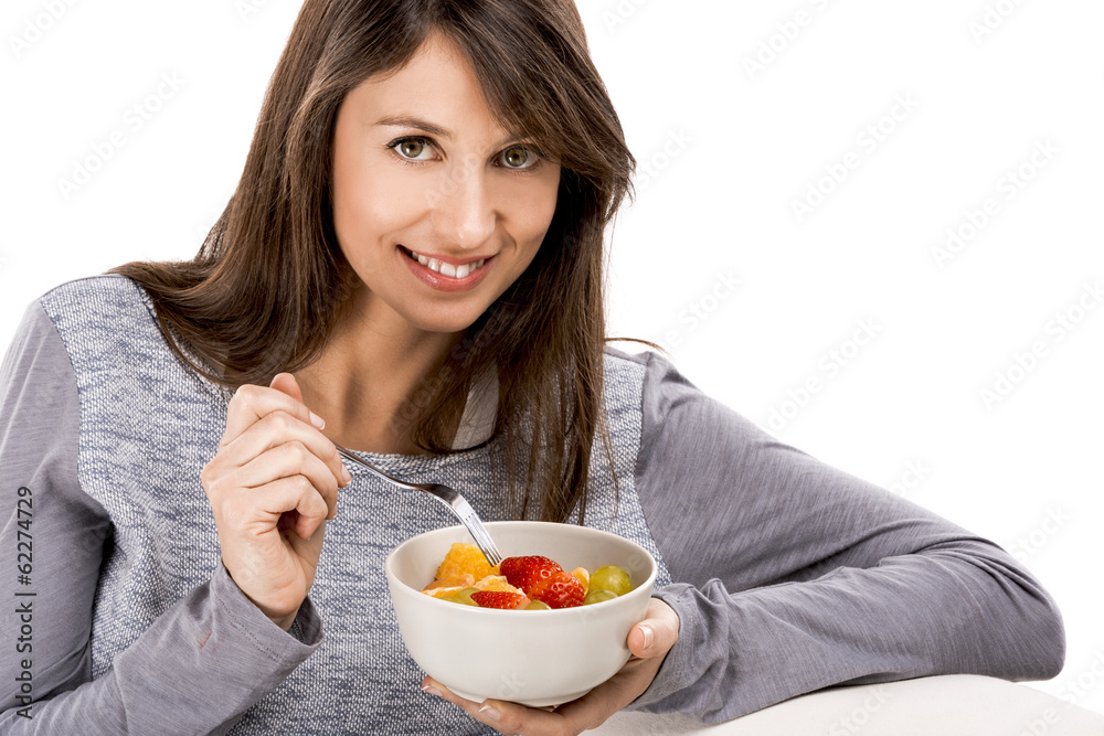 Beautiful woman relaxing on the sofa and eating a fruit salad Beautiful woman relaxing on the sofa and eating a fruit salad