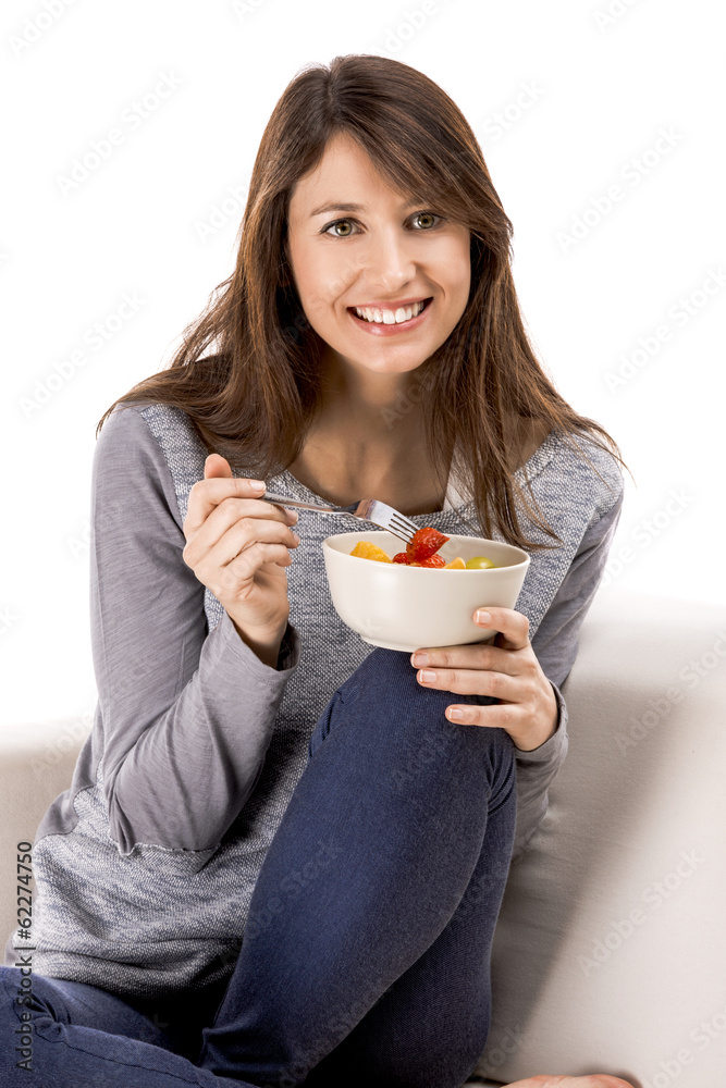 Beautiful woman relaxing on the sofa and eating a fruit salad Beautiful woman relaxing on the sofa and eating a fruit salad