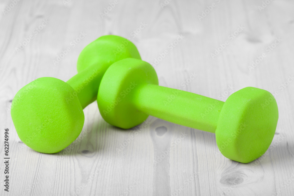 small green dumbbells on wooden surface small green dumbbells on wooden surface