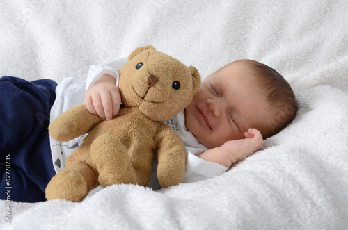 Newborn mit Teddy lacht