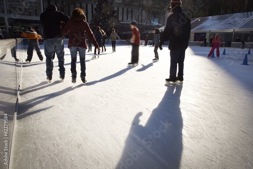 People ice skating in New York on sunny winter day