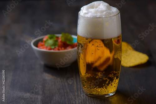 Beer with nachos and salsa in the background