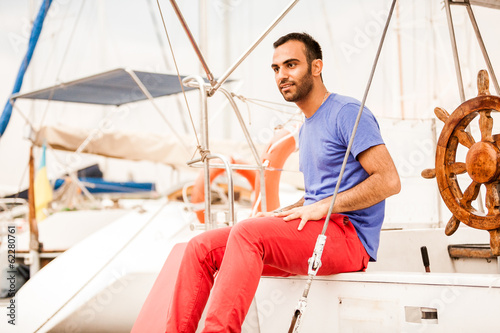 Stylish latin man sitting on yacht deck