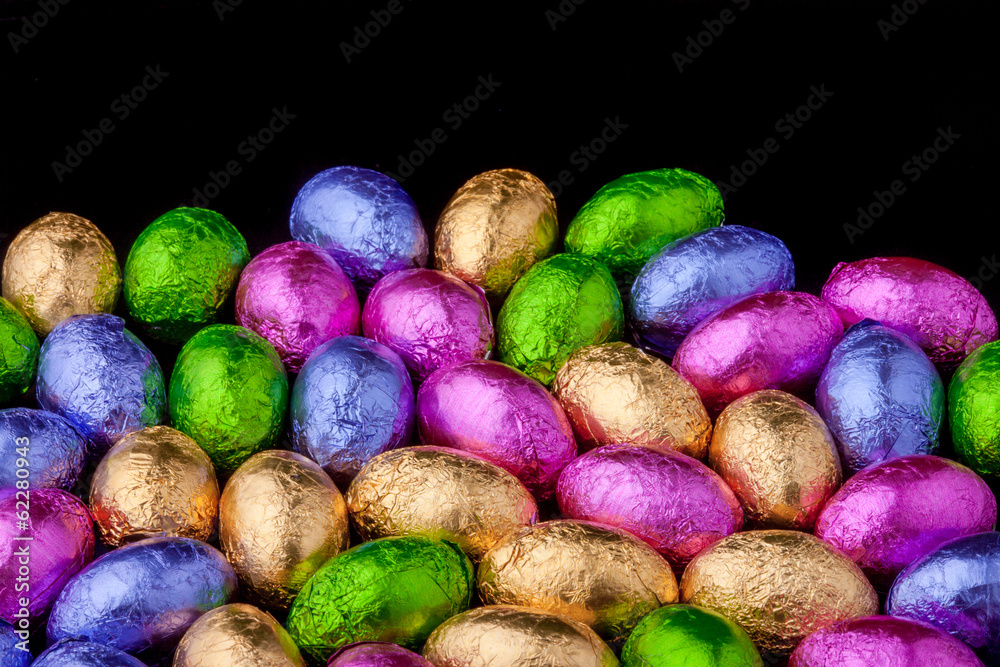 Chocolate Mini eggs wrapped in foil, black background Chocolate Mini eggs wrapped in foil, black background